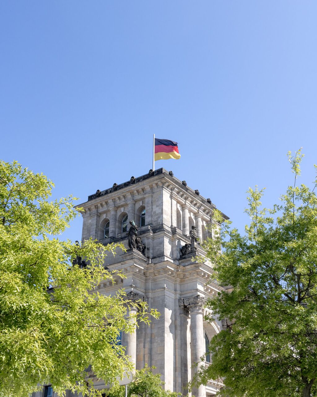 Behördengebäude mit Deutschlandflagge über den Baumkronen